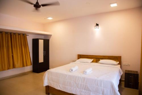 a bedroom with a bed with two towels on it at DE 28:11 GUEST HOUSE in Mapusa