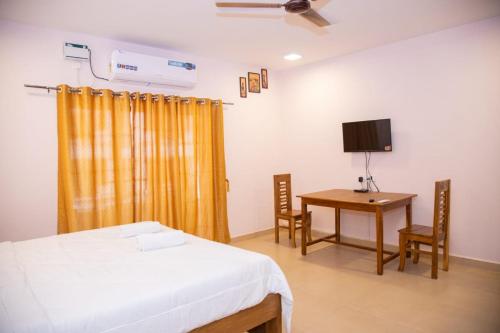 a bedroom with a bed and a desk and a television at DE 28:11 GUEST HOUSE in Mapusa