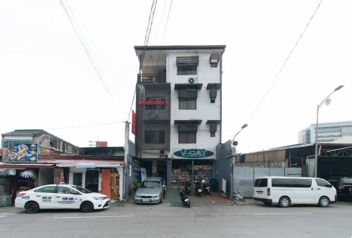 a white building with cars parked in front of it at RedDoorz at V-Cat Apartelle Sampaloc Manila in Manila