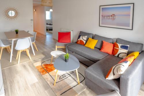 - un salon avec un canapé gris et des oreillers colorés dans l'établissement Aux portes de Bordeaux/\Les Carrelets/\MindUrGuest, à Lormont