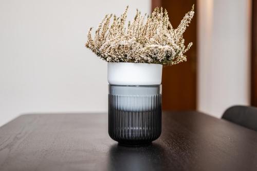 a black and white vase with dried plants in it on a table at Roma 23, SmartStay Rozzano in Rozzano
