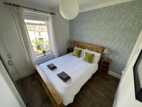a bedroom with a bed with green pillows and a window at Acacia House in Wolsingham