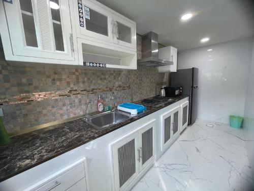 uma cozinha com armários brancos e um lavatório em Friend House BKK em Bangkok