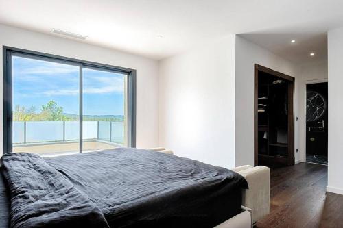 a bedroom with a bed and a large window at Villa Vice City -proche Eurexpo/Groupama stadium/LDLC Arena in Chamagnieu