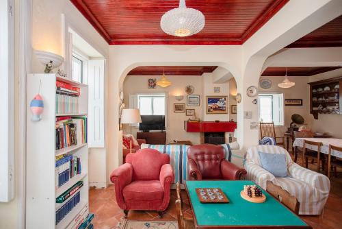 a living room with red chairs and a table at Torreira . Yellow Beach Pavilion in Torreira
