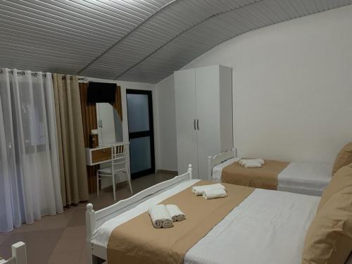a bedroom with two beds and a table and a mirror at Vogue Rooms in Golem