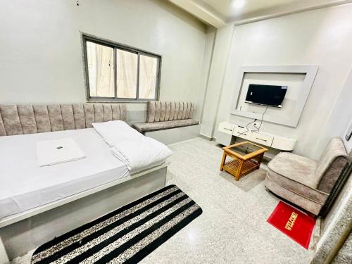 um quarto com uma cama, uma cadeira e uma televisão em HOTEL PRAKASH GUEST HOUSE ! Varanasi ! fully-Air-Conditioned hotel at prime location with off site Parking availability, near Kashi Vishwanath Temple, and Ganga ghat em Varanasi