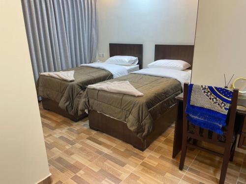 a bedroom with two beds and a chair in it at الأحفاد للشقق الفندقية Al Ahfad Hotel Apartments in Şāfūţ
