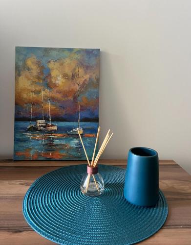 a table with a blue vase and a painting at Oceans Apartman in Dobra Voda