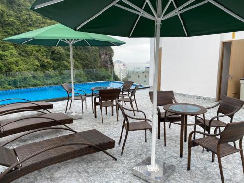 grupa krzeseł i stołów z parasolami przy basenie w obiekcie Sand Hotel w mieście Cát Bà