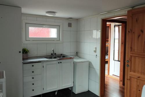 eine weiße Küche mit einem Waschbecken und einem Fenster in der Unterkunft Hus i Skärhamn när till hav och natur! in Utäng