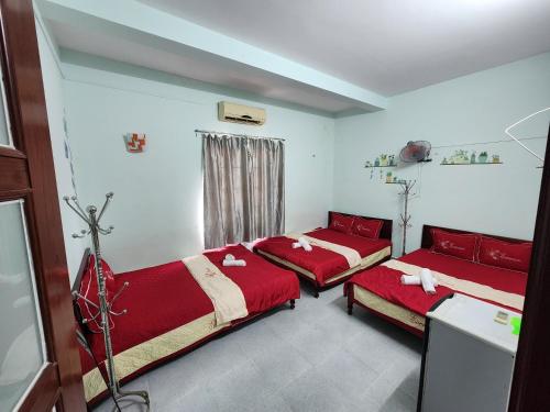 2 Betten in einem Zimmer mit roter Bettwäsche und einem Fenster in der Unterkunft Motel Thành Đạt in Vũng Tàu