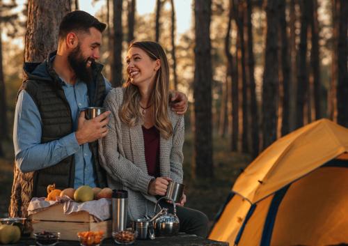 Un uomo e una donna in piedi davanti a una tenda di gyulai campingresort a Gyula
