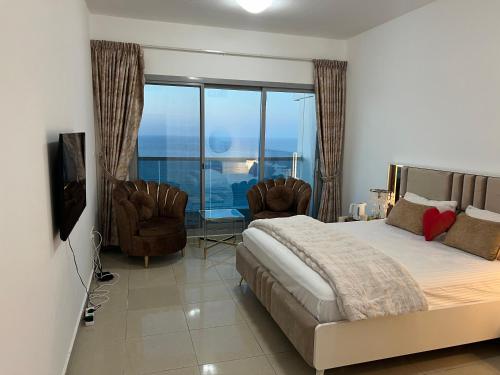 a bedroom with a bed and chairs and a balcony at Ft 22 R1 Luxury Room attach bath Seaview Beach access Ajman غرفة فاخرة مع إطلالة على البحر وإمكانية الوصول إلى الشاطئ in Ajman 