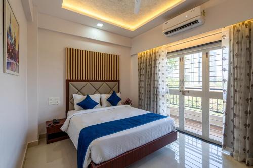 StayBird - Divine Suites, Business Hotel, Kharadi في بيون: غرفة نوم بسرير ونافذة كبيرة