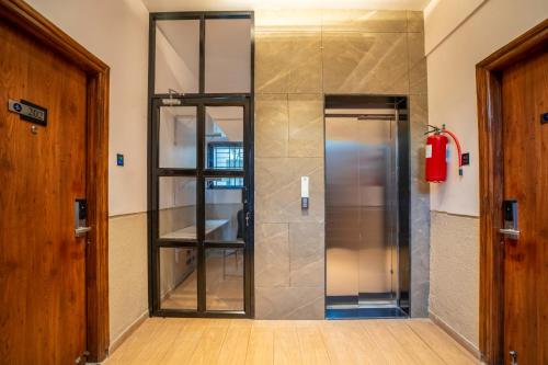 a glass elevator in a room with a door at StayBird - Divine Suites, Business Hotel, Kharadi in Pune