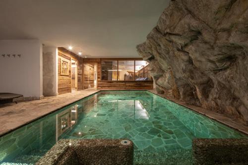 a swimming pool with a rock wall at La Tana dell'orso Hotel & SPA in Ponte di Legno