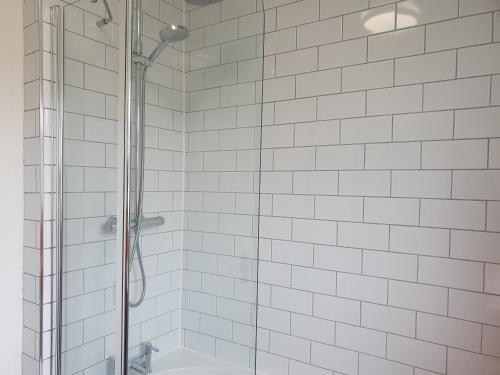 y baño con ducha de azulejos blancos. en Sunny Apartment In Cheltenham en Cheltenham