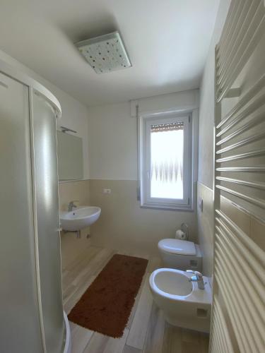 a bathroom with a sink and a toilet and a window at WoodenKey Asiago grazioso appartamento in centro in Asiago