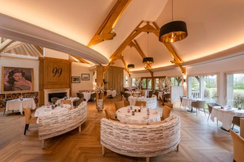 a restaurant with tables and chairs and a fireplace at Les Manoirs de Tourgéville in Deauville