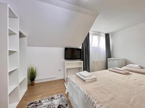 a white bedroom with a bed and a tv at Casa Coltea in Moieciu de Jos