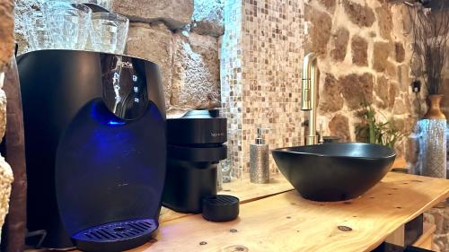 a black vase sitting on a wooden table with a bowl at Fisherman's hut in ‘Akko