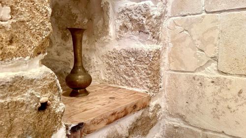 a vase sitting on a wooden shelf in a stone wall at Fisherman's hut in ‘Akko