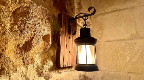 a light hanging on a wall with a stone wall at Fisherman's hut in ‘Akko