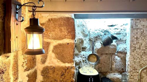 a light hanging from a stone wall next to a sink at Fisherman's hut in ‘Akko