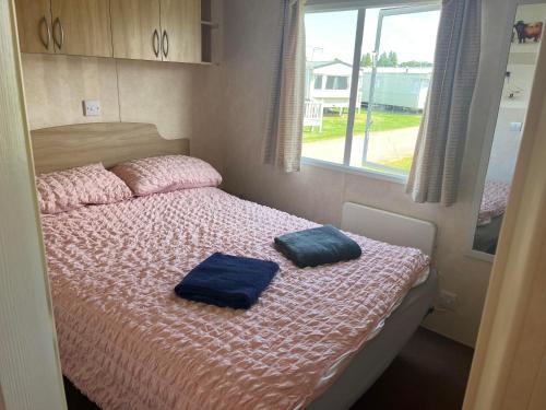 a bedroom with a bed with two blue pillows on it at Pets Stay free 2 bedroom caravan at heacham beach in Hunstanton