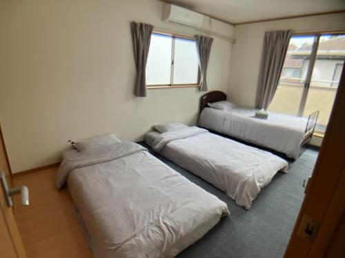 a room with three beds and a window at Akane Shimada House - Vacation STAY 13990 in Narashino