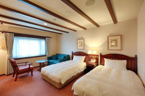 a hotel room with two beds and a blue chair at Sun Members Hirugano in Gujo