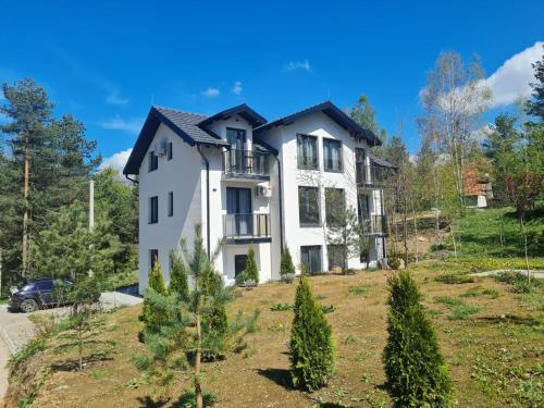 una casa blanca en una colina con árboles en Apartman VIN 5, en Divčibare
