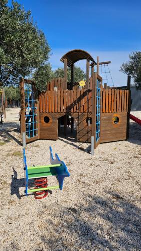a wooden playground with a slide and a play structure at Mobile Homes Albatross Pirovac in Pirovac