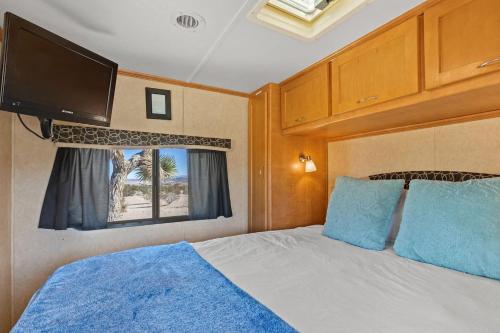 een slaapkamer met een bed en een flatscreen-tv bij JT Village Campground - Casa Pequena in Joshua Tree