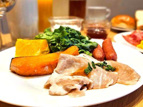 a white plate of food with vegetables and meat at APA Hotel Higashi Shinjuku Kabukicho Higashi in Tokyo