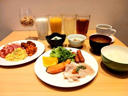 two plates of food on a wooden table with drinks at APA Hotel Higashi Shinjuku Kabukicho Higashi in Tokyo