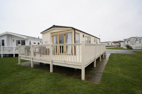 a tiny house on a deck in a yard at Caravan - Sleeps 8 - Pets Ok - Parking in Hunstanton
