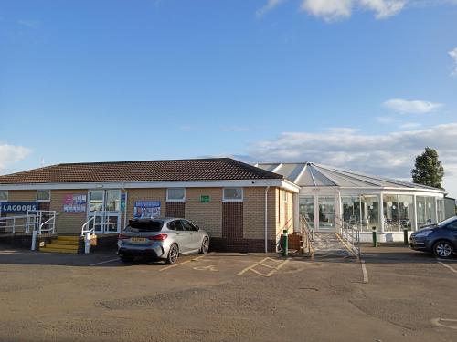 a building with a car parked in a parking lot at pets stay free 3 bedroom caravan at heacham beach in Heacham