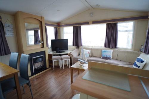a living room with a couch and a tv at pets stay free 3 bedroom caravan at heacham beach in Heacham