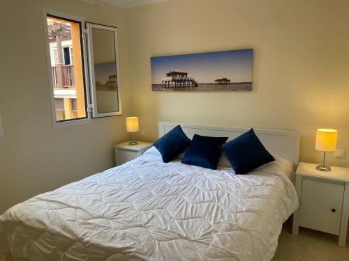een slaapkamer met een wit bed met blauwe kussens bij MONTE CARRERA Sunrise & Sunset in Mogán