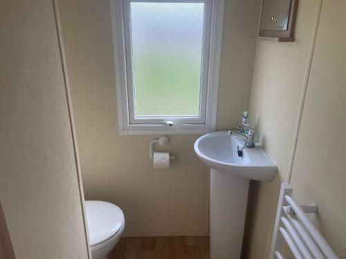 a bathroom with a toilet and a sink and a window at 2 bedroom caravan in hunstanton free wi-fi in Hunstanton