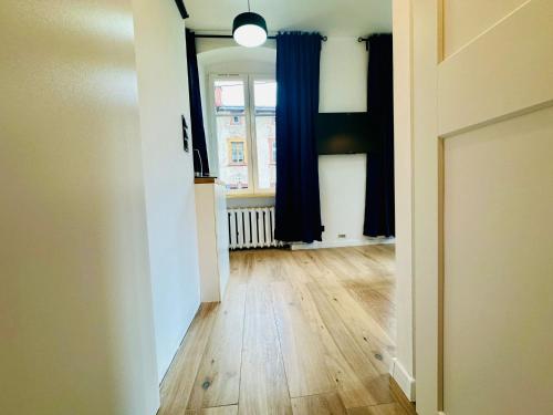 pusty pokój z drewnianą podłogą i niebieskimi zasłonami w obiekcie Apartamenty Maj Sokołowsko w mieście Sokołowsko
