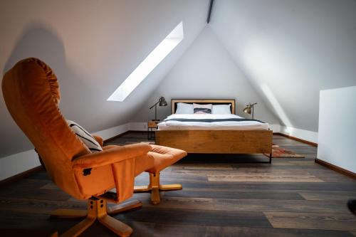 a bedroom with a bed and a chair in a attic at Apartament Loftowy Ordona 5 in Szczecinek