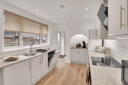 a kitchen with white cabinets and a sink at The Bay Escape -Lovely 3bd house in Cardiff