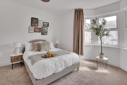 biała sypialnia z łóżkiem i oknem w obiekcie The Bay Escape -Lovely 3bd house w Cardiff