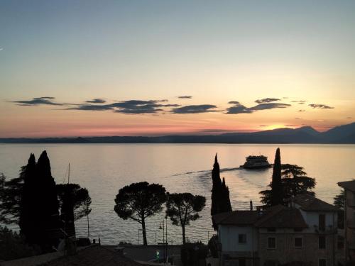 a boat on the water with a sunset in the background at Hotel Ristorante Al Caminetto WorldHotels Crafted Adults Only in Torri del Benaco