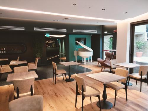 トッリ・デル・ベーナコにあるHotel Al Caminetto WorldHotels Crafted Adults Onlyのピアノ、テーブル、椅子が備わるレストラン