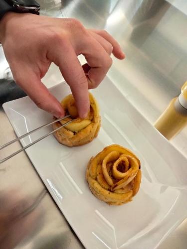 a person cutting into two onion rings on a plate at Hotel Ristorante Al Caminetto WorldHotels Crafted Adults Only in Torri del Benaco
