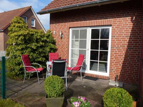 eine Terrasse mit Stühlen, einem Tisch und einem Fenster in der Unterkunft Ferienhaus Sandmann Greetsiel in Greetsiel